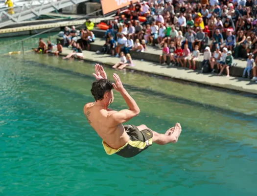 A person is performing a manu into the water at the Auckland Manu event