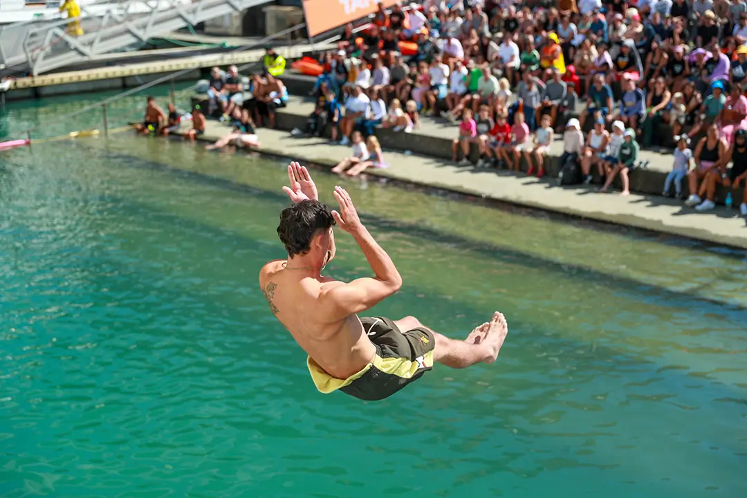 A person is performing a manu into the water at the Auckland Manu event