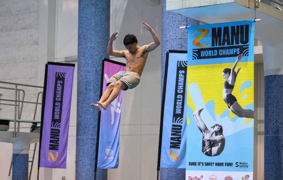 A young person is jumping into a pool, mid-manu