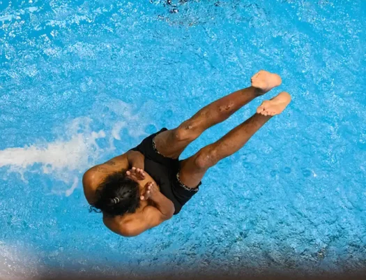 Looking from above, at a person about to splash into the water, performing a manu