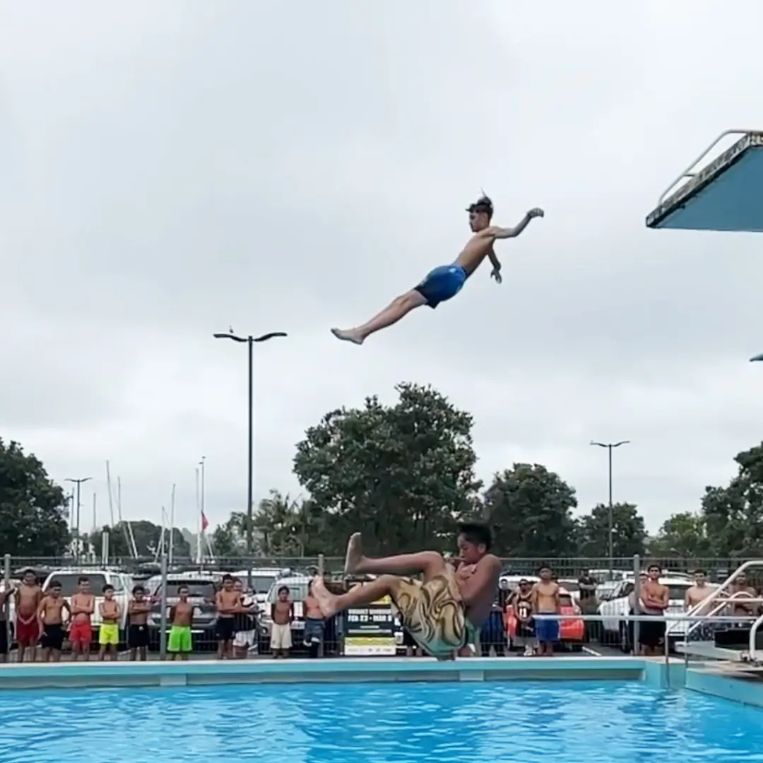 Two youth mid-manu into a diving pool